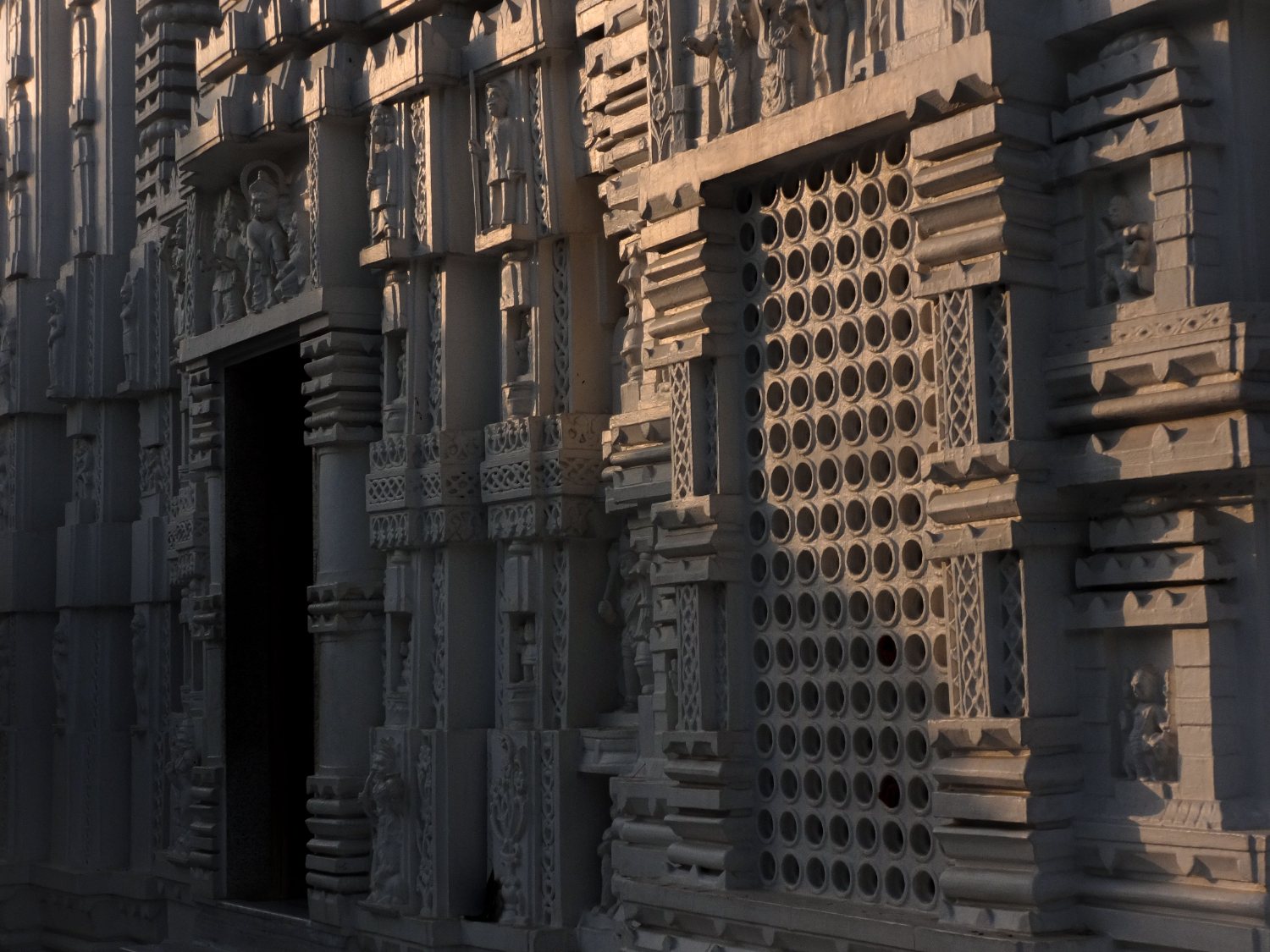 Dark stone temple facade with pierced screens